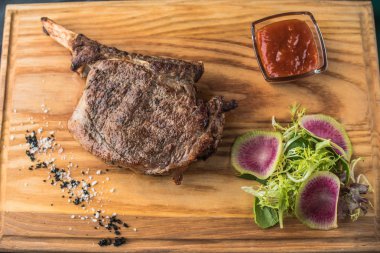 Domates sosu ve ahşap tahta üzerinde taze salata Izgara t-bone biftek