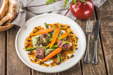 Havuç ile sığır eti ve ahşap masa üzerinde sunulan beyaz tabakta sos