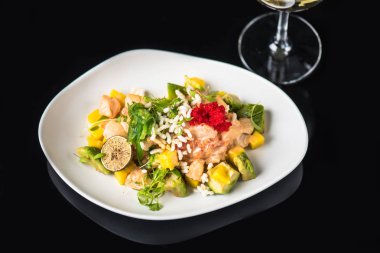 İncelik sebze salatası kadeh beyaz şarap ile siyah arka plan üzerine tabakta servis