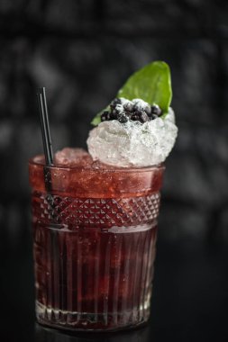 Yaprak ve koyu arka plan üzerinde yaban mersini taze kokteyl cam süslenmiş