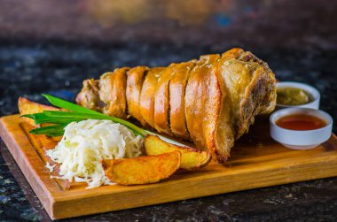 Domuz knuckle kavrulmuş patates ve lahana ile üzerinde ahşap kurulunda görev yapmaktadır.