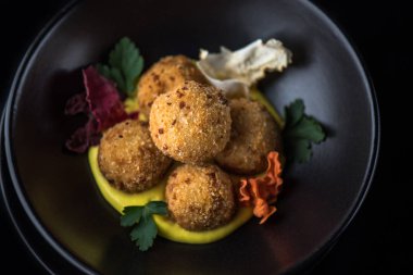 Derin kızarmış peynir topu yığılmış siyah kase sos ile servis