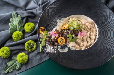 Vejetaryen risotto kadeh beyaz şarap ile restoranda masa örtüsü üzerinde siyah plaka servis