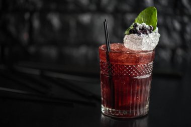 Yaprak ve koyu arka plan üzerinde yaban mersini taze kokteyl cam süslenmiş