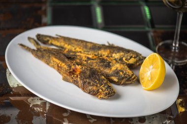 kızarmış balıkla limon kahverengi yüzeyi beyaz plaka üzerinde