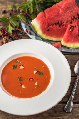 Çorba gaspaço taze karpuz ile ahşap masa beyaz tabakta servis