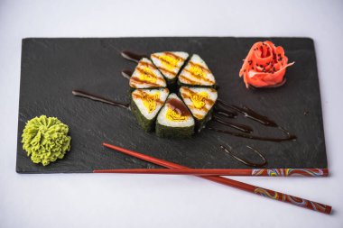 zencefil, wasabi, soya sosu ve gri arka plan üzerinde kayrak gemide yemek çubukları ile lezzetli üçgen suşi
