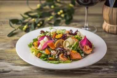 Ahşap masa üzerinde beyaz plaka üzerinde kızarmış tavuk ile sebze salatası