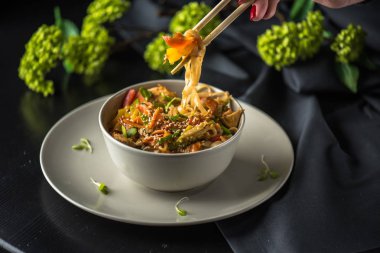 Çubuk üzerinde kase Asya deniz ürünleri erişte koyu arka plan üzerinde tutan el