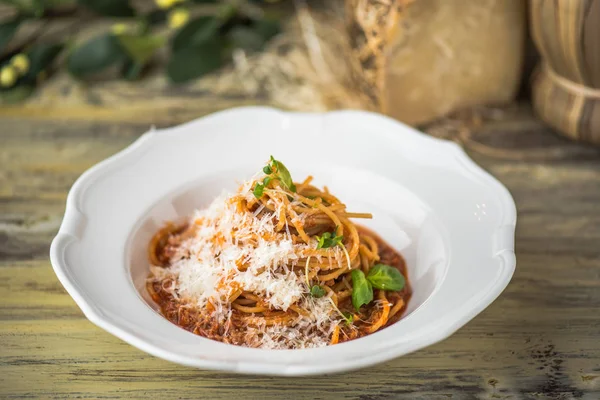 Ahşap masa üzerinde beyaz tabakta servis domates soslu makarna çeşitleri
