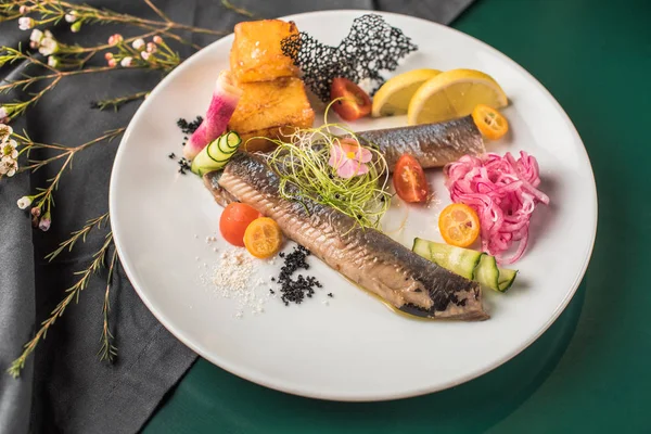 青鱼在盘子里用蔬菜在绿色的食物上服务 — 图库照片