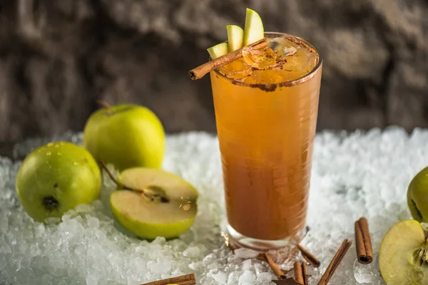 Cocktail with apple and cinnamon in glass on ice with ingredients