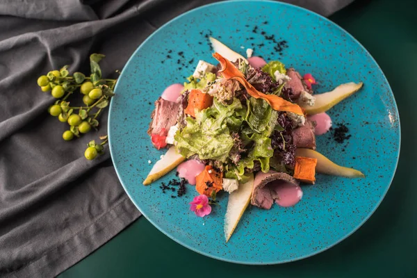 Kızarmış ördek karanlık yüzeyi mavi tabakta servis ile taze sebze salatası