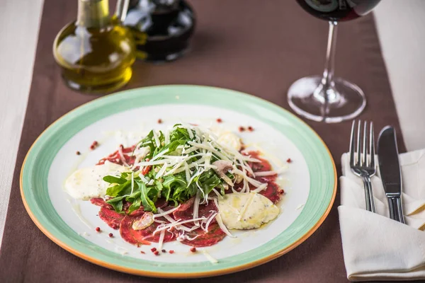 Etli meze peynir ve roka plaka masada kırmızı şarap ile