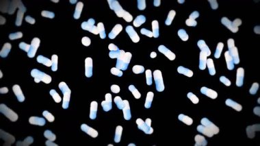 Siyah arka planda bir sürü tıbbi kapsül uçurmak. Tıp ve eczacılık konsepti. Mavi hap kapsülünün 3 boyutlu animasyonu dönüyor. Döngü canlandırması.