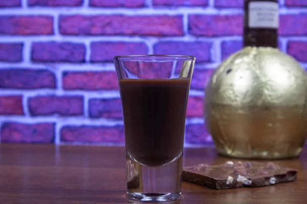 Chocolate liqueur in a shot glass and a piece of chocolate