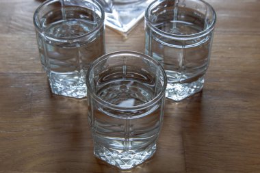 Üç bardak votka ahşap bir masa üzerinde