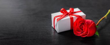 Sevgililer günü hediyesi kırmızı gül ve modern ahşap arka plan siyah kalpler. Sevgiliye arka plan. Görüntü