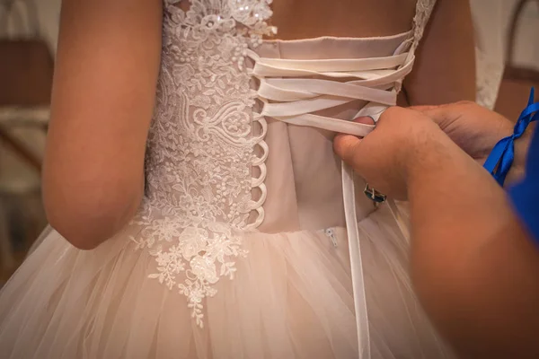 On the corset of the wedding dress, a friend of the bride helps to tighten the lacing