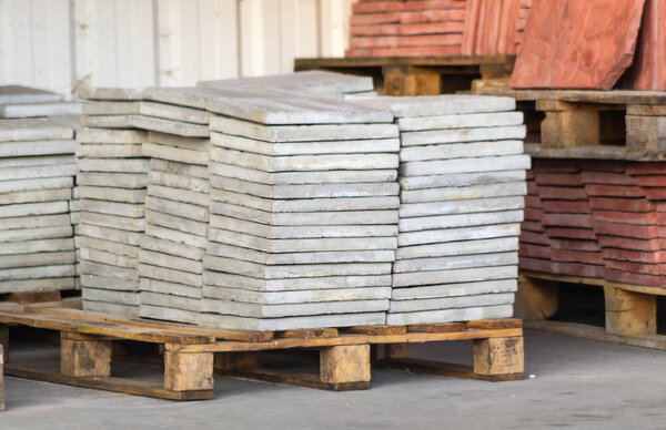 Paving slabs factory. Tiles piled in pallets. Warehouse paving slabs in the factory for its production