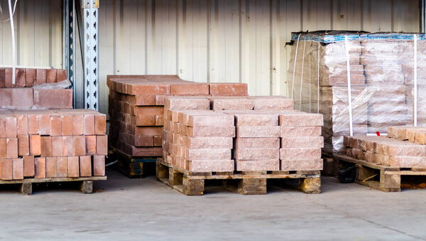 Paving slabs factory. Tiles piled in pallets. Warehouse paving slabs in the factory for its production