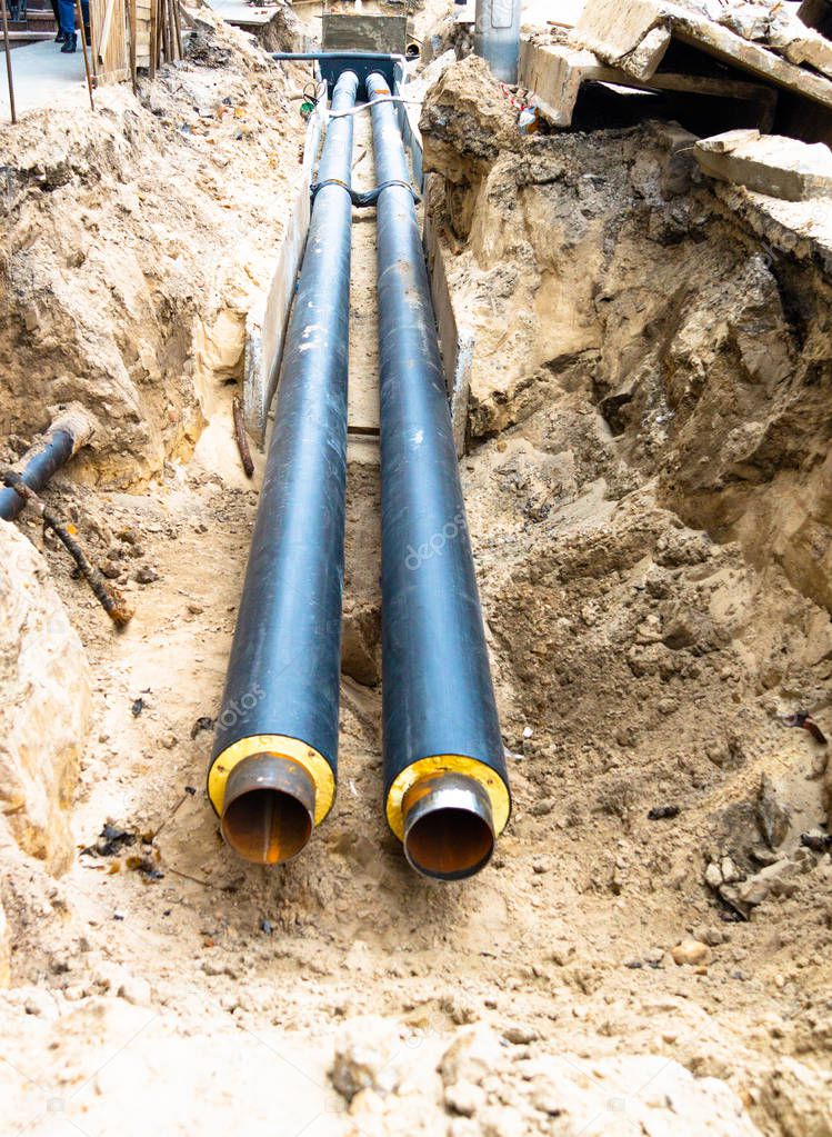 Water pipes in ground pit trench ditch during plumbing under construction repairing.