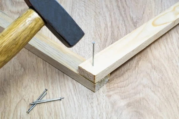 Martello martelli un chiodo in un blocco di legno . — Foto Stock
