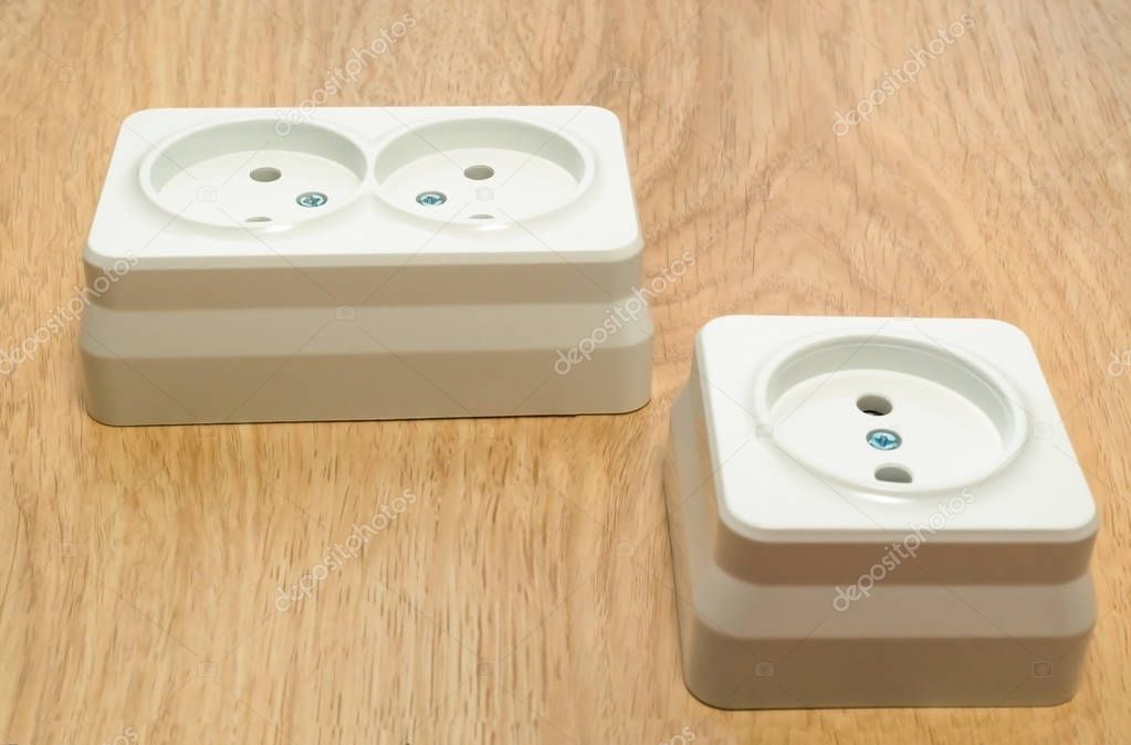 Close-up of a white outlet on a wooden table.