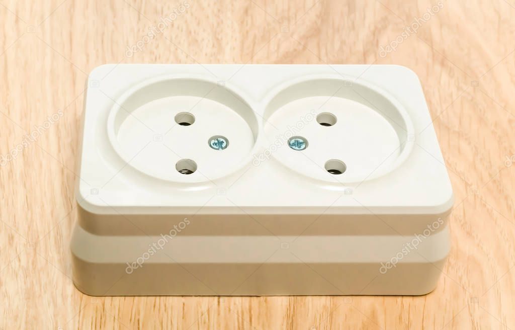 Close-up of a white outlet on a wooden table.