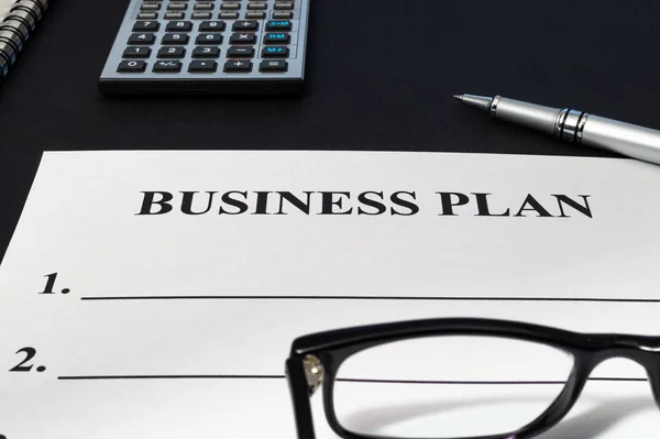 Plan de negocios de estrategia con pluma, calculadora y cuaderno en mesa oscura . — Foto de Stock