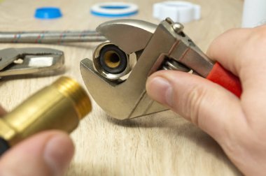 Ahşap arka planda esnek su besleme tüpleri ve ayarlanabilir anahtar üzerinde closeup.