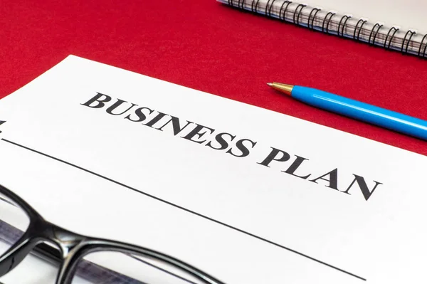 Plan de negocio de estrategia con bolígrafo, gafas y dinero en mesa roja . — Foto de Stock