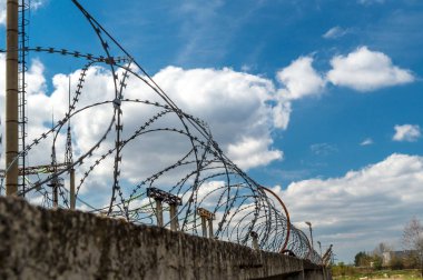 Mavi gökyüzüne karşı dikenli tel ile Tuğla duvar.