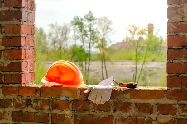 Een paar handschoenen en een Masons helm bij de bouw. — Stockfoto
