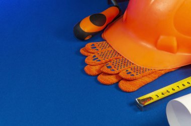 Mavi masa üzerinde koruyucu kask, eldiven ve bant ölçüsü.