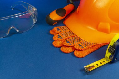 Mavi masa üzerinde koruyucu kask, eldiven ve bant ölçüsü.