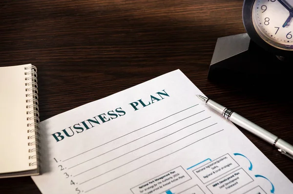 Plan de negocio de estrategia con bolígrafo y bloc de notas sobre mesa marrón . — Foto de Stock