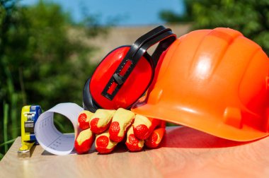 Ahşap arka planda koruyucu sert şapka, kulaklık, eldiven, gözlük ve rulet, kopya alanı.