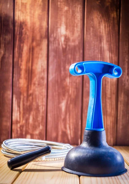 Clean plastic plunger with blue handle and cable on wooden background — Stock Photo, Image