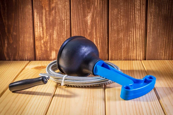 Desatascador de plástico limpio con mango azul y cable sobre fondo de madera — Foto de Stock