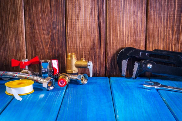 Plumbing supplies and tools on a blue wooden background close-up. — Stock Photo, Image