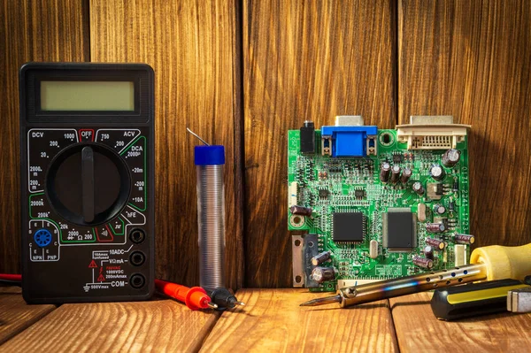 Electric tester and electronics tool kit on wooden background.