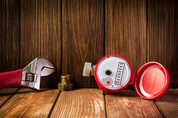 New water meter with fittings and wrench on a vintage wooden background. — Stock Photo, Image