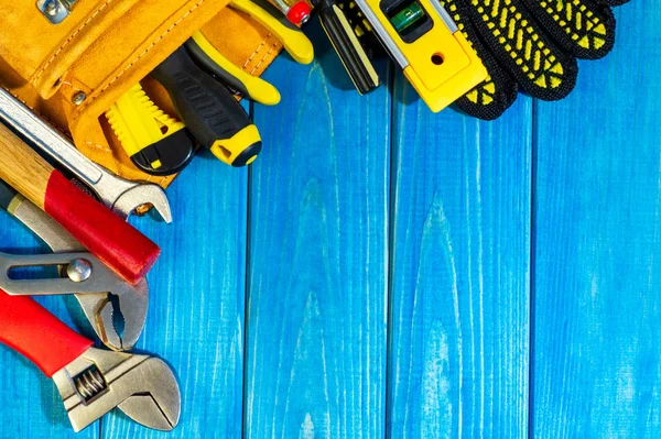 Notwendiges Werkzeug in einer Tasche auf blauem Holzgrund. — Stockfoto