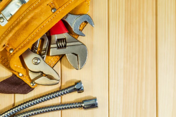 Noodzakelijke set van tools in de zak voor loodgieters op een houten achtergrond. — Stockfoto