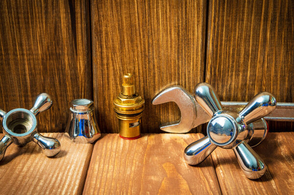 Plumbing repair accessories and tools on wooden background.