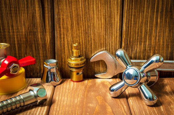 Plumbing repair accessories and tools on wooden background.