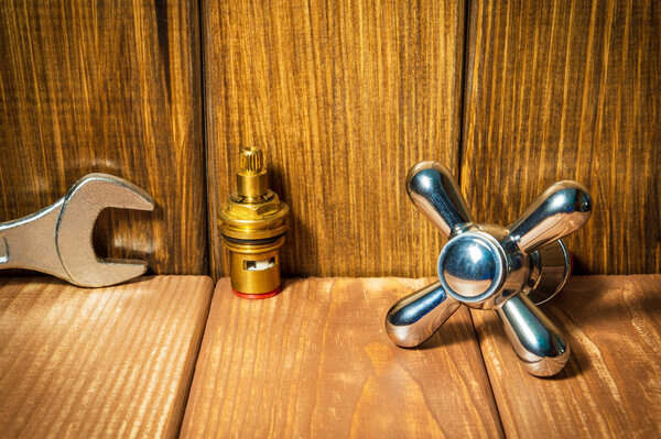 Plumbing repair accessories and tools on wooden background.