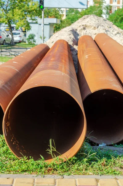 Varios tubos de metal que yacen en la calle para la colocación de aguas residuales . — Foto de Stock