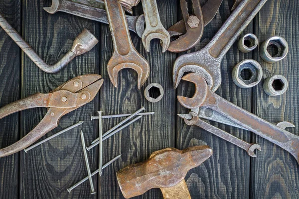 Rusty old tools are laid out on black vintage wood background. — Stock Photo, Image